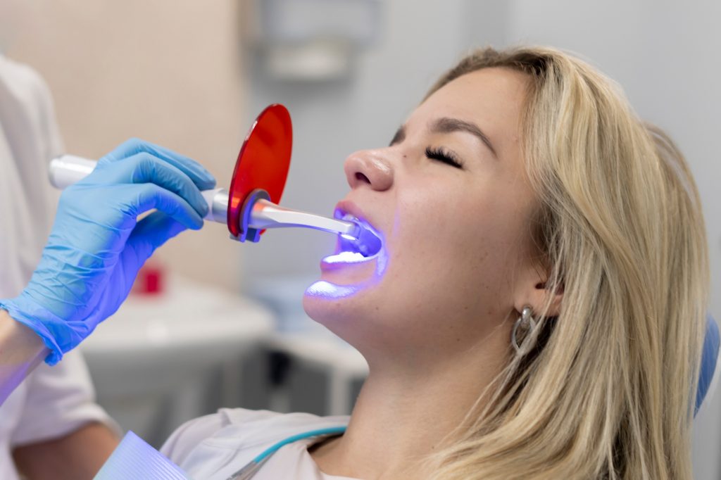 a young girl on a teeth whitening treatment, using ultraviolet lamp for bleaching