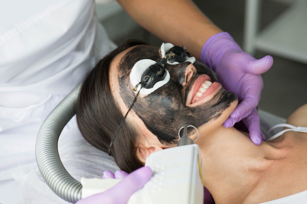 Cute woman gets a face peeling procedure in a beauty salon. Skin care