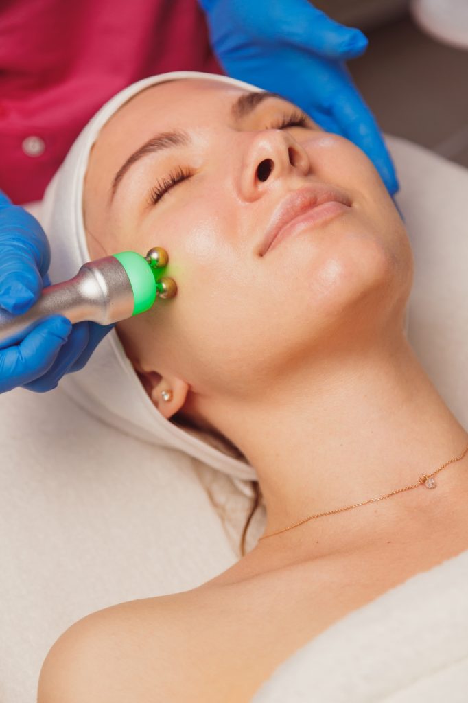Young woman getting microcurrents skin cleansing and face treatment